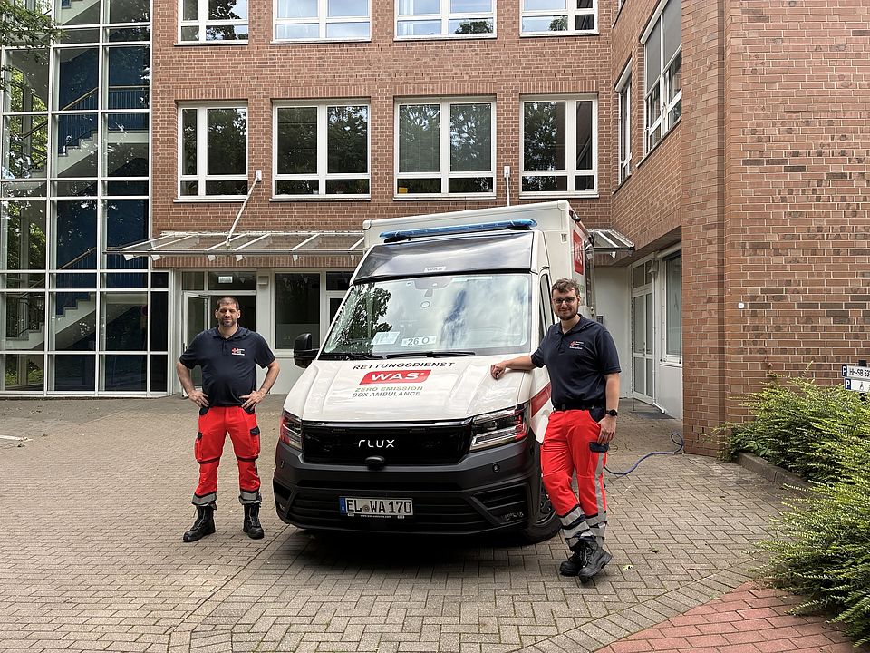 Zwei DRK-Mitarbeiter stehen vor einem Rettungswagen